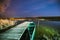 Real Night Sky Stars Above Old Pier With Moored Wooden Fishing Boat. Natural Starry Sky And Countryside Landscape With