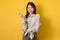 Real people portraits. Happy young Asian woman with dark hair looking at camera and smiling over yellow background