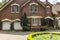 Real photo of a brick house with a bay window, garages and round