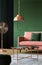 Real photo of a copper coffee table, lamp and fan next to a powder pink sofa in a living room interior