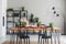 Real photo of cozy dining room interior with a table full of vegetables and herbs, and black shelf in the background