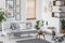 Real photo of a grey living room interior with a sofa, plants, fruit in a bowl and paintings