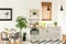 Real photo of a modern kitchen interior with cupboards, plants, shelves and pink accessories next to a dining table and chairs