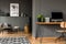 Real photo of open space home interior of a freelancer with simple workspace at the front and a living room with gray armchair in