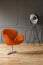 Real photo of orange armchair and big metal studio lamp standing