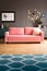 Real photo of powder pink sofa with fur cushion standing in dark