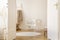 Real photo of white cradle with heart standing in Scandi kid room interior with teddy bear, herringbone parquet and empty wall