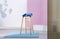 Real photo of a wooden bar stool with a blue seat standing on a