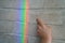 A real rainbow on the wall of brick wallpaper. Child`s hand wants to touch rainbow light reflection