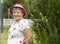 Real Smiling Senior Woman In Hat In Sunny Day Looks At Camera. Green Trees, Park on