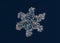 Real snowflake at high magnification. Macro photo of small snow bubbly crystal, snowflake glowing on dark blue