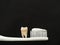 Real tooth on white toothbrush with toothpaste on black background. Good healthy teeth concept