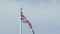 Real Union Jack flag of the United Kingdom on flagpole fluttering in the wind