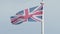 Real Union Jack flag of the United Kingdom on flagpole fluttering in the wind