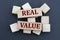 REAL VALUE - words on wooden bars on cubes on a gray background