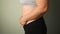 Real view of women body fat belly. Obese woman hand holding excessive belly fat. Fat woman trying to zip up her