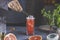 Real woman preparing pink Grapefruit Mezcal Paloma Cocktail in highball glass with water drops on table in real home. New life