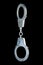 real zinc plated steel police handcuffs closed hanging vertically, isolated on black background