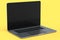 Realistic aluminum laptop with empty white screen isolated on yellow background.