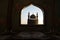 A realistic Arabian interior miniature with window and columns. Silhouette of muslim praying on carpet near window. Festive