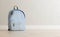 Realistic baby blue backpack on the wooden floor and light beige wall in the background, close up, mock-up, poster