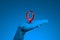 Realistic blue human hand holding red map pin geotag isolated on blue background. 3d rendering