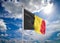 Realistic flag. 3D illustration. Colored waving flag of Belgium on sunny blue sky background