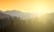 Realistic illustration of a mountain landscape with a forest. Sun shining with sunshine and rays under the morning yellow orange