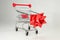 Realistic iron mini shopping cart with plastic parts with a red Christmas bow. Object for purchases such as sales