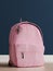 Realistic millennial pink backpack on the wooden floor and prussian blue wall in the background, close up, mock-up