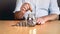 Realistic Photo Concept of Saving Money: Man in Shirt Putting Coins into Glass Jar at Table AI-Generated Image