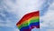 Realistic rainbow flag of an LGBT organization waving against a blue sky. LGBT pride flags include lesbians, gays