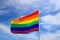 Realistic rainbow flag of an LGBT organization waving against sky. LGBT pride flags include lesbians, gays, bisexuals and