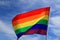 Realistic rainbow flag of an LGBT organization waving against sky. LGBT pride flags include lesbians, gays, bisexuals and