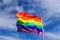 Realistic rainbow flag of an LGBT organization waving in a sky. LGBT pride flags include lesbians, gays, bisexuals and transgender