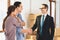 Realtor with family in new apartment with cardboard boxes. Husband and realtor are shaking hands.