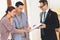 Realtor with family in new apartment with cardboard boxes. Woman is signing contract.