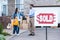 realtor making deal with single mother with sold signboard blurred