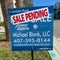 A realtor sign in front of a condo that says Sale Pending