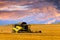 Reaping machine or harvester combine on a wheat field with a very dynamic sky