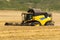 Reaping machine or harvester combine on a wheat field with a very dynamic sky as background