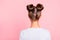 Rear back behind view of nice attractive groomed girl wearing two fashionable buns over pink pastel background