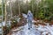 Rear of a female walking on the snowy path in the forest, trees around and yellowing grass around