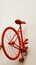 The rear half of a vintage red bicycle pinned to the wall of a minimalist building block