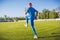 Rear horizontal view of active young male athlete running and jogging alone along a green football lawn in stadium while out