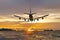 Rear image commercial passenger aircraft or cargo airplane fly over coast of sea after takeoff from airport in evening with golden