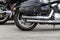 Rear part of a motorcycle: wheel, exhaust pipe and black leather wardrobe trunk luggage bag close-up,