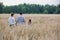 Rear photograph of a loving young family walking through a corn field during summer holding hands