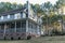 Rear side view of a large two story blue gray house with wood and vinyl siding