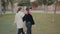 rear tracking view of two stylish girls wandering around a park holding hands